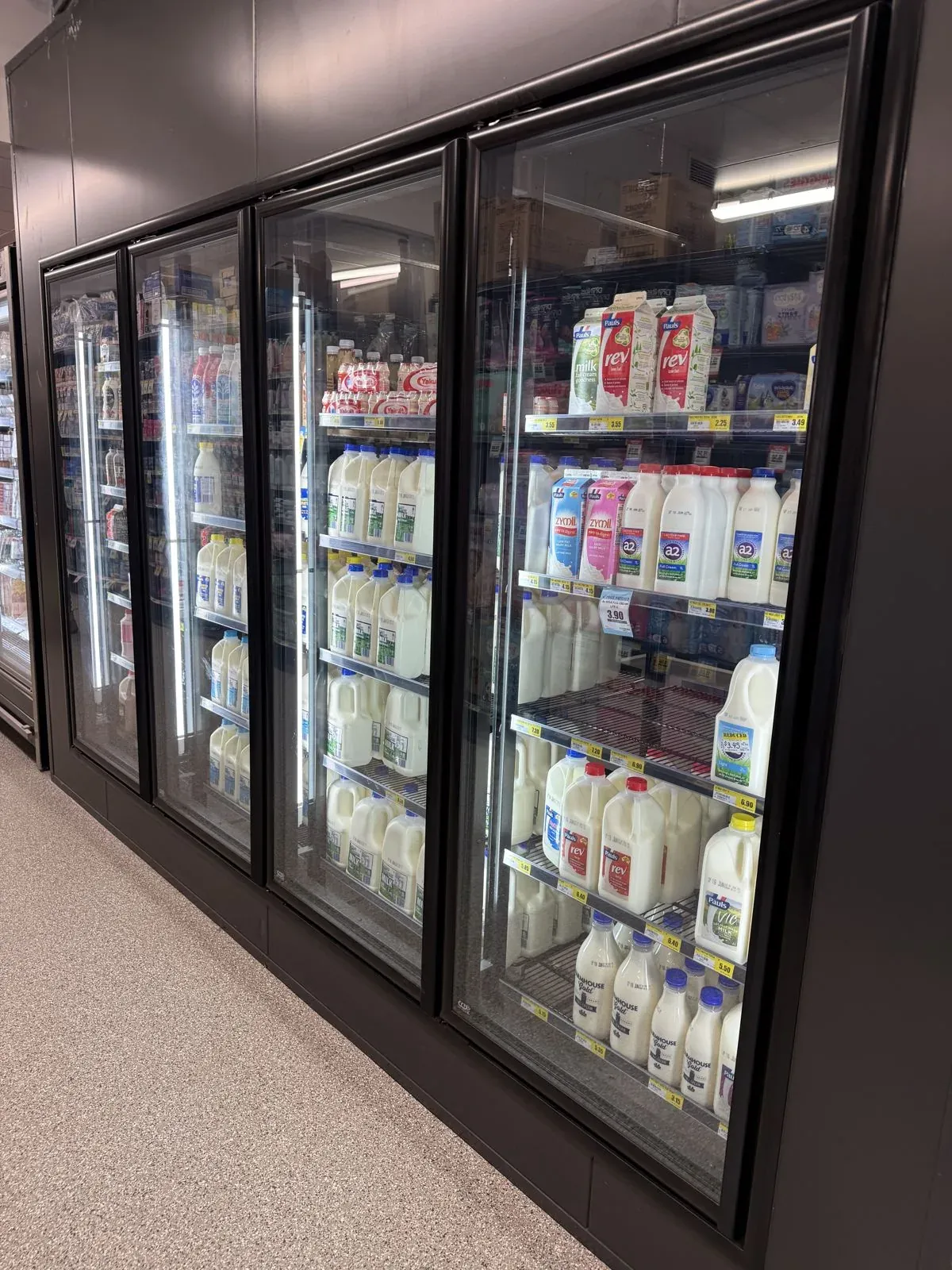 Glass-door cool room display stocked with milk in a local supermarket